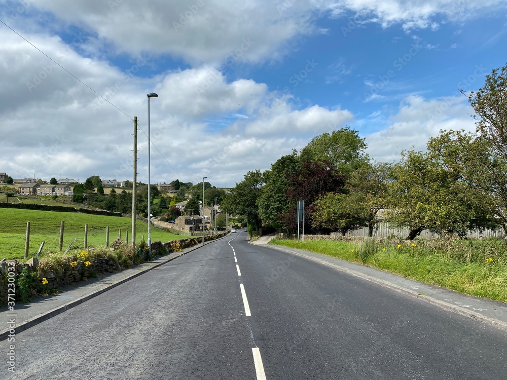 Main road, leading down into Keelham, with dry stone walls, fields and trees near, Denholme, Bradford, UK
