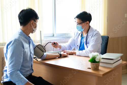 Young female Doctor taking the blood pressure of a patient in doctor office at hospital photo