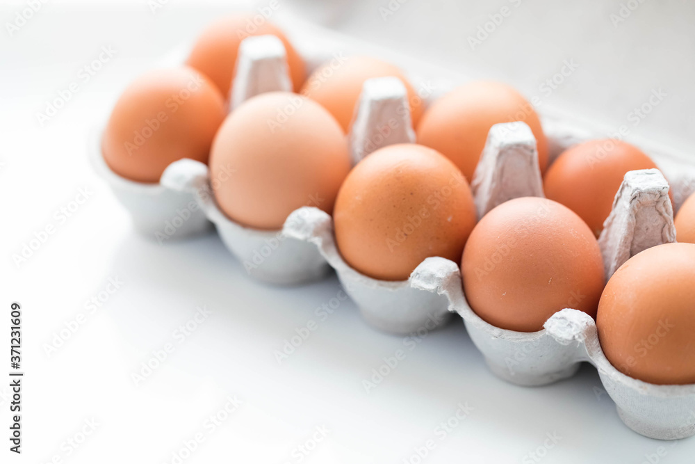 large brown chicken eggs in a box for 10 eggs. The box is open, Copyspace
