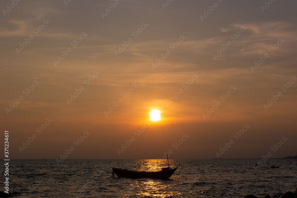 Fototapeta premium Silhouette of a fishing boat in the middle of the picture, in the evening there is a sunset at the sea