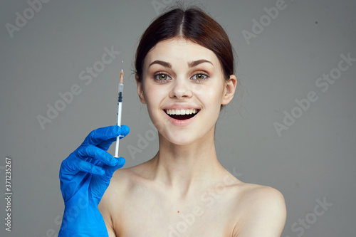 Woman in blue gloves with syringe in hand with botox injection treatment against wrinkles