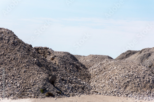 Industrial background with pile of gravel in front of the sky. Extraction of gravel. Construction of roads. Piles of gravel on construction site. Morning. Beautiful light.