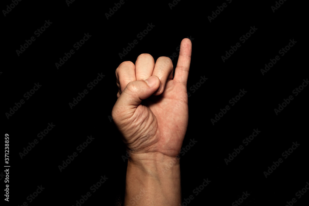 The man's hand holding the little finger shows the symbol of a contract or a request for reconciliation on black background. The man's hand holding the little finger shows the symbol of a contract or a request for reconciliation on black background.