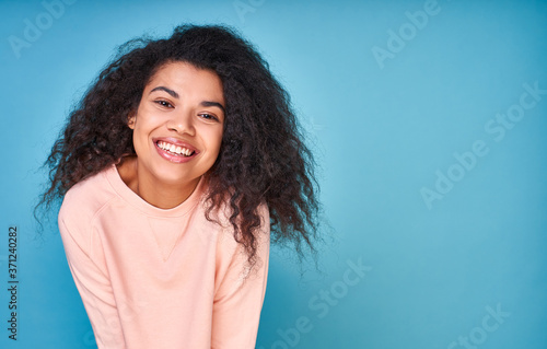 A happy optimistic curly ethnic girl smiles.