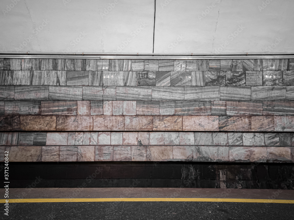 Fototapeta premium The empty wall of the subway station is lined with gray marble.