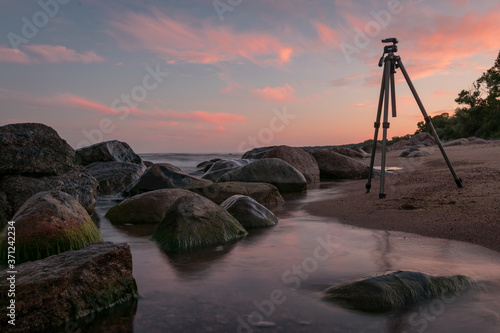 rocky seashore before sunrise, photo stand by the sea, dark stone silhouettes and colorful sky