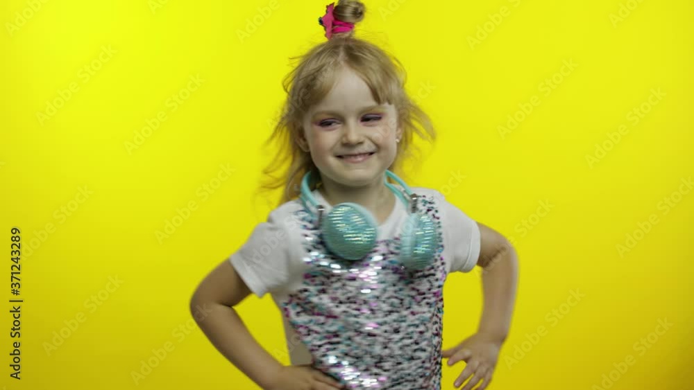 Child with headphones, showing thumb up. Relaxing, enjoying, having hun on yellow background Child with headphones, showing thumb up. Relaxing, enjoying, having hun on yellow background