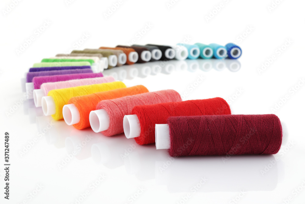 colored cotton reels in an arc on white with shallow depth of field colored cotton reels in an arc on white with shallow depth of field