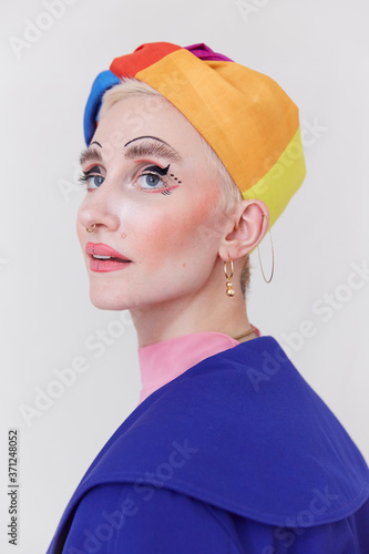 A stylish woman wearing a beautiful rainbow hat and a unique makeup look. photo