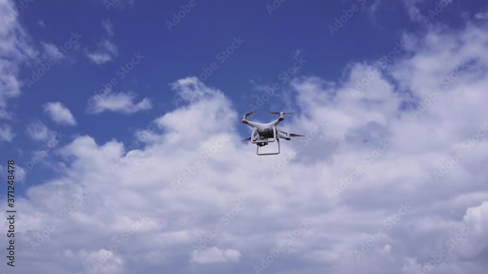 Drone coming in, hovering and leaving the frame on a cloudy summer day Drone coming in, hovering and leaving the frame on a cloudy summer day