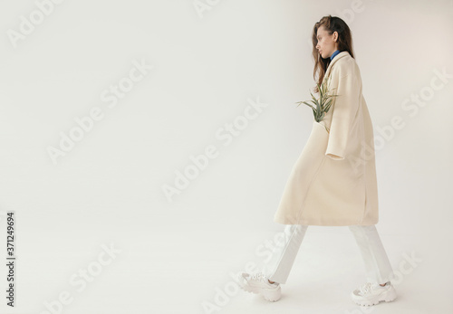 Stylish woman walking with plant in coat photo
