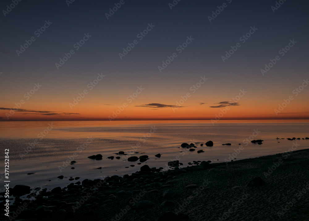 Naklejka premium orange sunset by the sea, black stone silhouettes against the sea background, summer