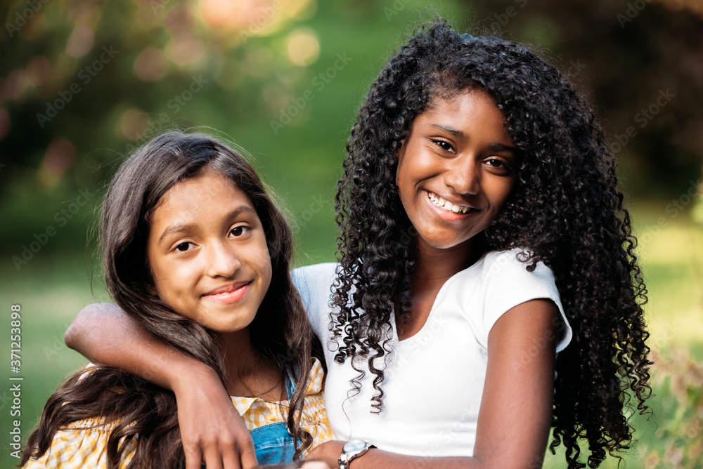 portrait of smiling ethnic girlfriends looking at camera portrait of smiling ethnic girlfriends looking at camera