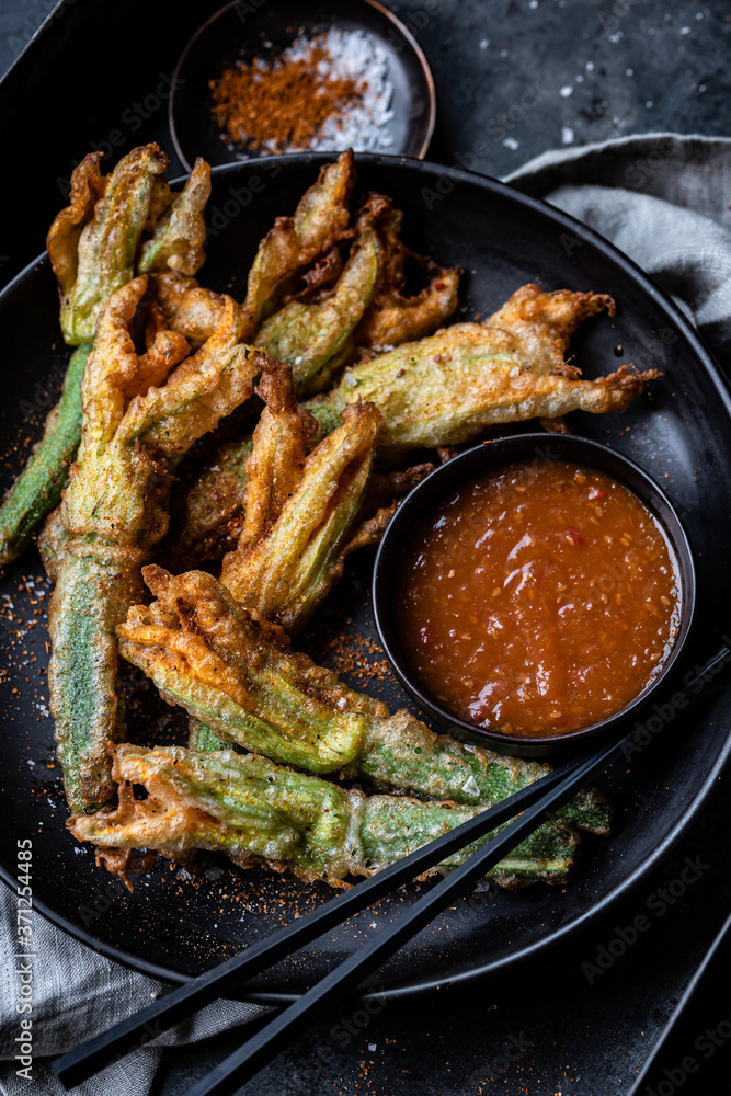 Zucchini flowers in tempura with spicy sauce and spices Stock Photo