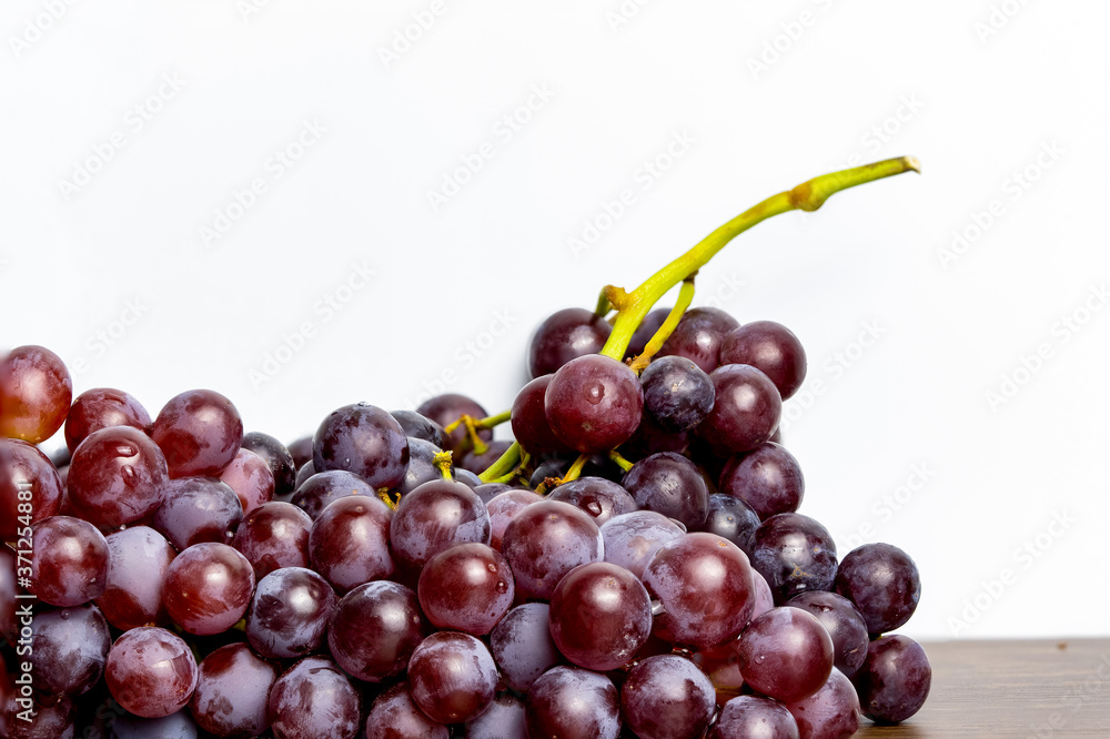 Close-up of red seedless grapes with water droplets on a white background Close-up of red seedless grapes with water droplets on a white background
