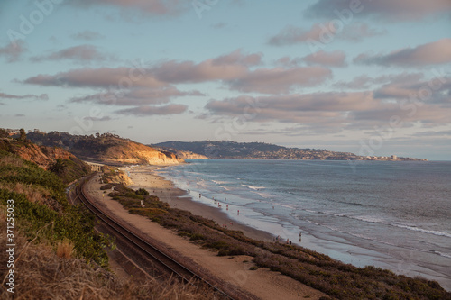 A railroad track along the beach and ocean on a sunny afternoon. 