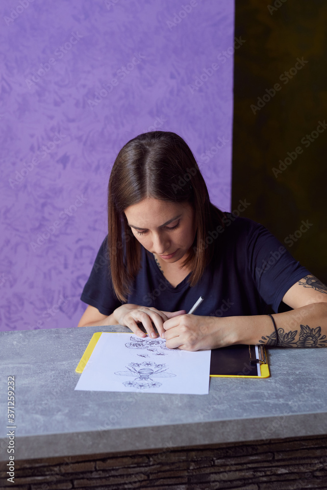 Young woman drawing a tattoo on the paper. Young woman drawing a tattoo on the paper.