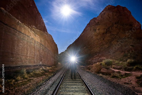 Person lighting up canyon with a headlamp on train tracks, Moab Utah photo