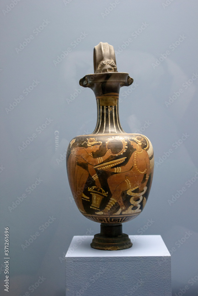 A ancient greek vase in a display with a blue background A ancient greek vase in a display with a blue background