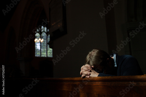Man bows his head in prayer in Church.