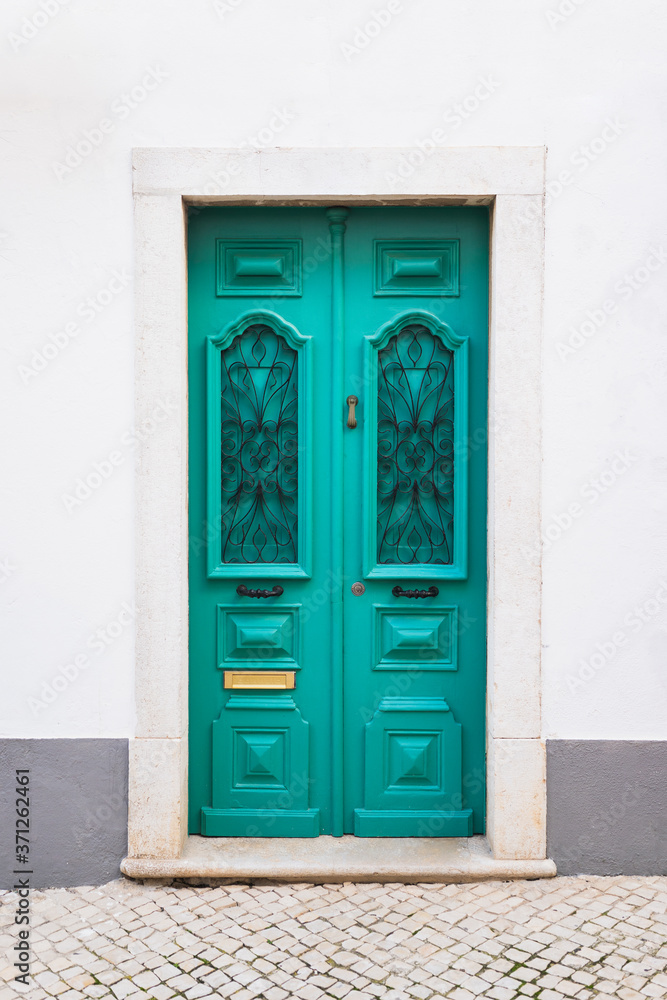 Old turquoise decorated door in the white building Old turquoise decorated door in the white building