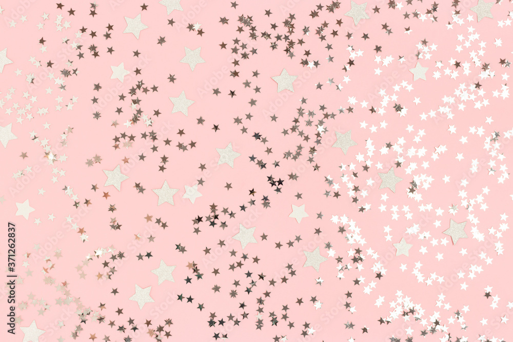 Glowing silver stars confetti on a pink pastel background. Festive beautiful backdrop.