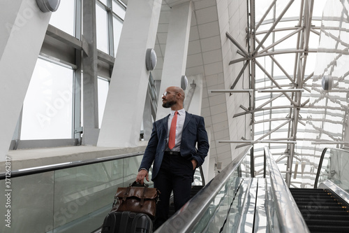 Businessman on escalator looking out window photo