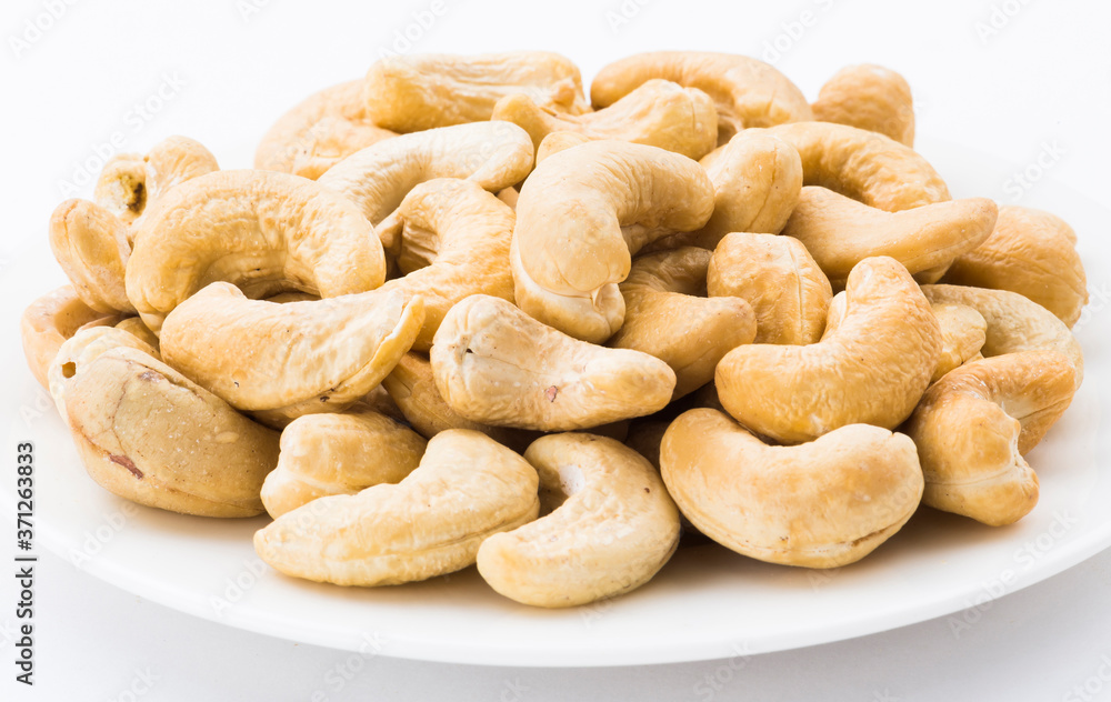 fresh cashew nuts on a white dish above the white background fresh cashew nuts on a white dish above the white background