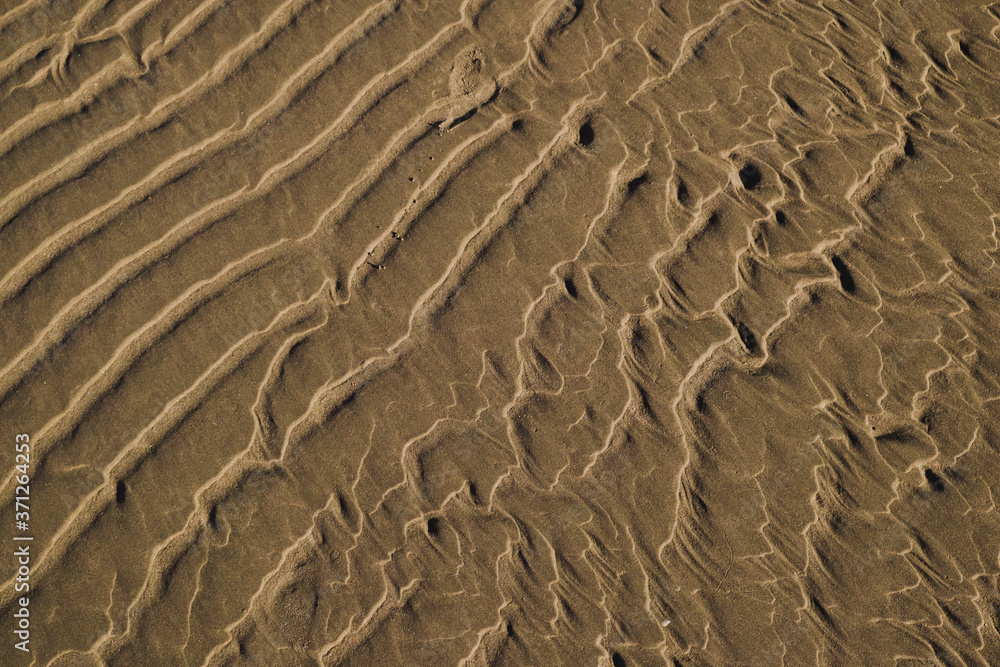 Close up of golden sand shaped by the ocean retiring during low tide