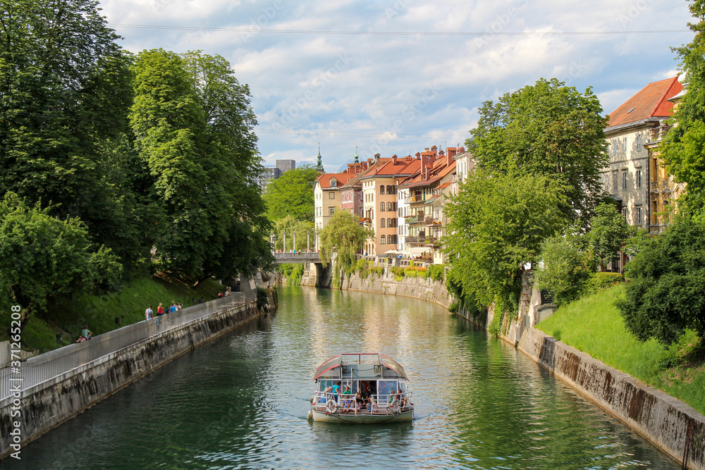 A tourist boat travelling along the Ljublijanica River in afternoon in Ljubljana