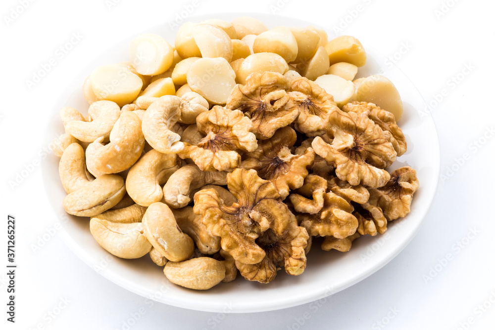 Variety of fresh nuts on a white dish above the white background Variety of fresh nuts on a white dish above the white background