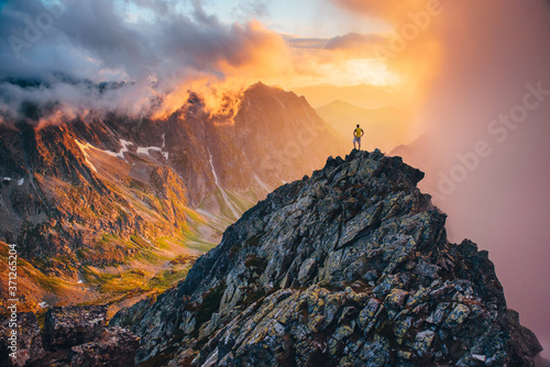 Man on the top of the hill watching wonderful scenery in mountains during summer colorful sunset in High Tatras in Slovakia.. photo