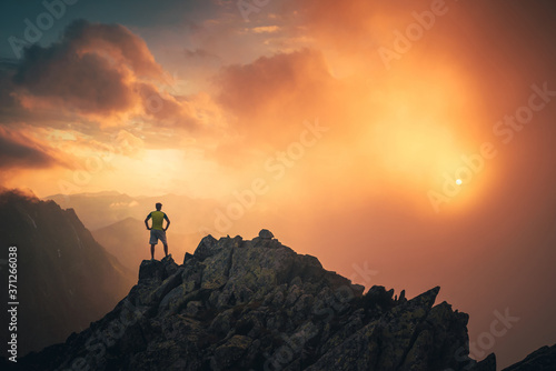 Hiker on the top of the hill looking at beautiful sunset sky. Silhouette of young hiker, edit space. Travel, adventure or expedition concept..