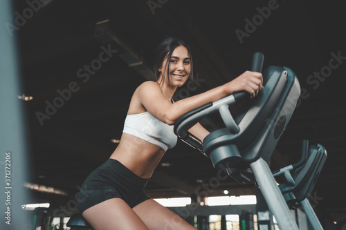 Fitness girl is engaged on a stationary bike. Pretty young woman loses weight in the gym