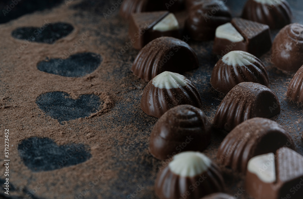 chocolates on black stone with cocoa powder forming hearts