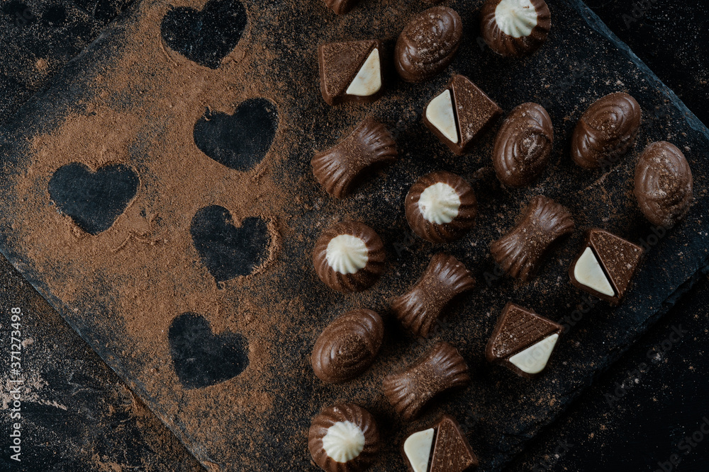 chocolates on black stone with cocoa powder forming hearts