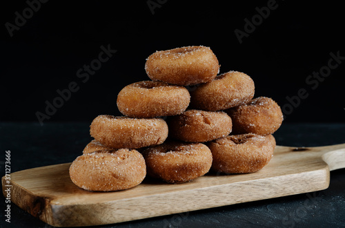 sugar donuts on wooden board with black background