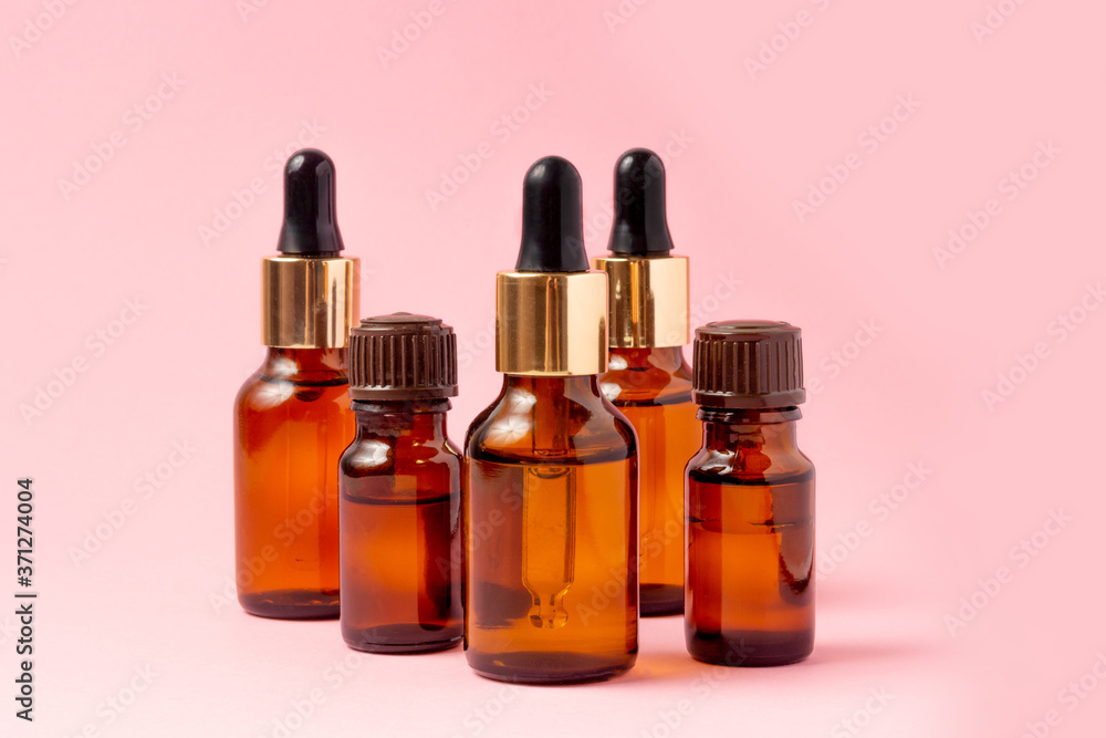 A set of amber bottles for essential oils and cosmetics. Glass bottle on a pink background. Dropper, spray bottle A set of amber bottles for essential oils and cosmetics. Glass bottle on a pink background. Dropper, spray bottle