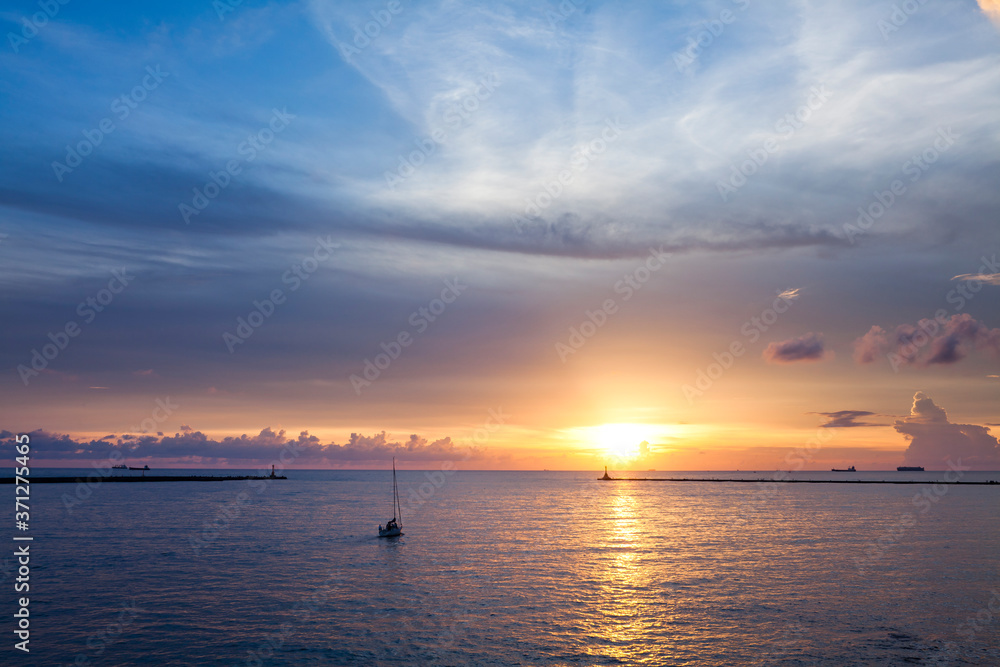 Sunset landscape with sailboat sailing on the sea.