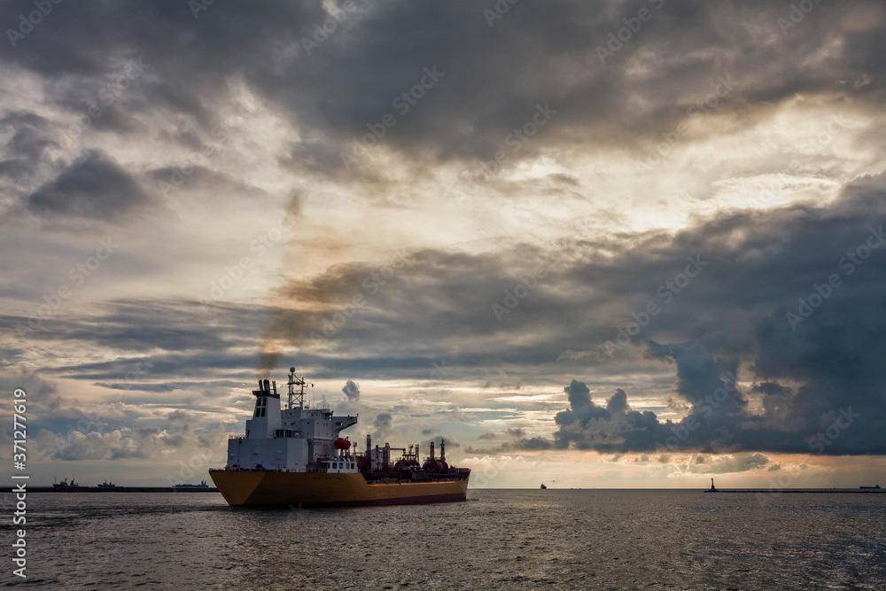 Fototapeta premium Sunset into the sea with the large ship silhouette.