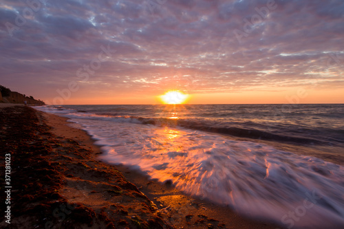 Beautiful sunrise at the sea on a cloudy morning. Sandy shore with seaweed. Black sea. Sanzhiika. Ukraine