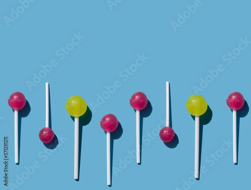 caramel on a stick on a blue background, chupa chups pattern, red and yellow lollipop wave