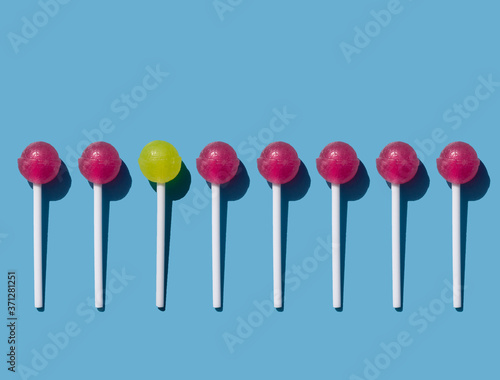 caramel on a stick on a blue background, chupa chups pattern, red and yellow lollipop © AGolovach