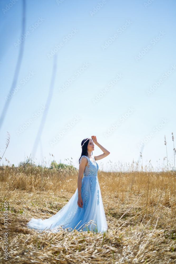 Portrait of a tender girl in a blue long dress in dry peas with a smile on her face on a sunny warm summer day Portrait of a tender girl in a blue long dress in dry peas with a smile on her face on a sunny warm summer day