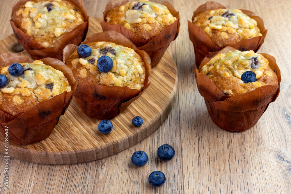 blueberry muffins with scattered berries on the wooden table