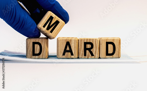 Text DMARD made from wooden cubes. Hands in a blue glove. photo