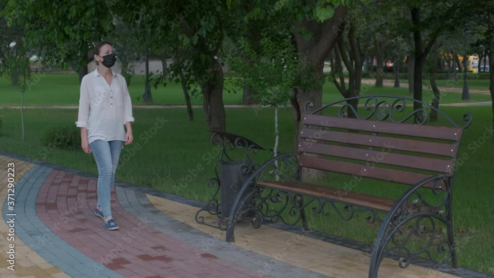 Walking in a mask. Pretty woman in a medical mask walks in the park. Walking in a mask. Pretty woman in a medical mask walks in the park.