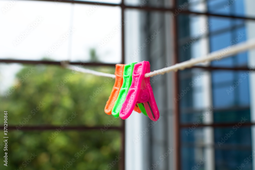 A trio of colourful plastic clothes pegs hanging on a washing line with blurred background