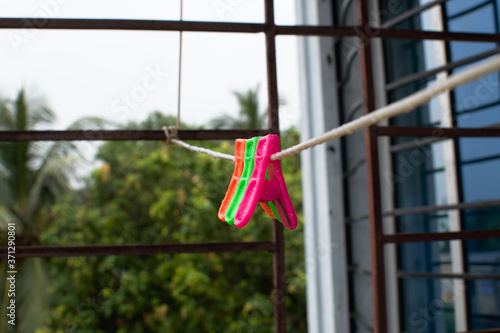 A trio of colourful plastic clothes pegs hanging on a washing line with blurred background