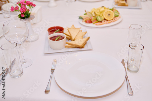 Table set with sparkling wineglasses  plates with serviette and cutlery on table  copy space. Place setting at wedding reception. Table served for wedding banquet in restaurant